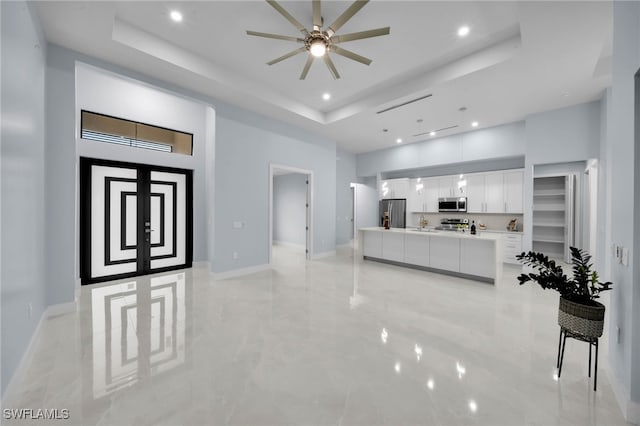 interior space featuring recessed lighting, a tray ceiling, baseboards, and a high ceiling