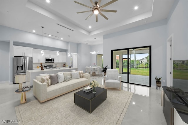 living room with recessed lighting, a tray ceiling, a towering ceiling, and a ceiling fan