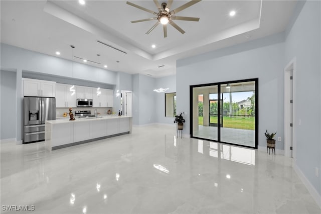 living room featuring baseboards, a tray ceiling, recessed lighting, a high ceiling, and marble finish floor