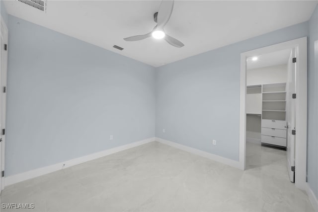 unfurnished bedroom with a ceiling fan, a spacious closet, baseboards, and visible vents