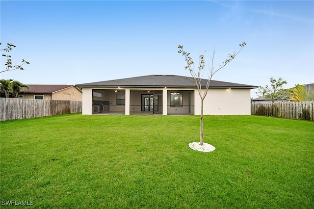 rear view of house featuring a yard, a fenced backyard, and stucco siding