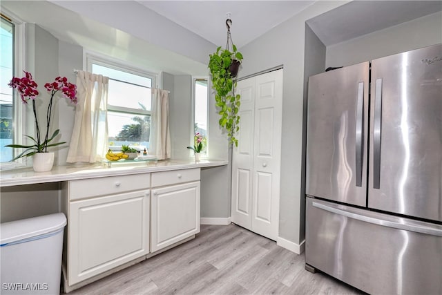 kitchen featuring light wood-style flooring, white cabinetry, freestanding refrigerator, and light countertops