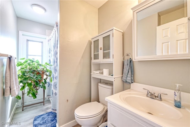 bathroom with baseboards, toilet, wood finished floors, and vanity