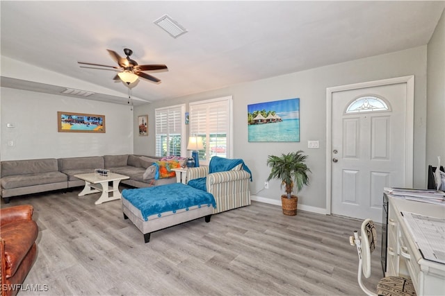 living room with visible vents, light wood-type flooring, and a ceiling fan