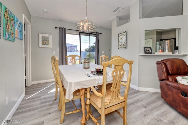 dining space featuring light wood-style flooring, baseboards, visible vents, and a chandelier