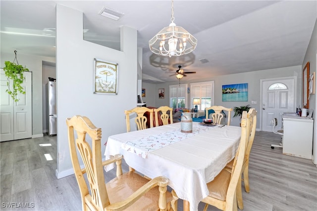 dining area featuring visible vents, light wood-style flooring, ceiling fan with notable chandelier, and baseboards