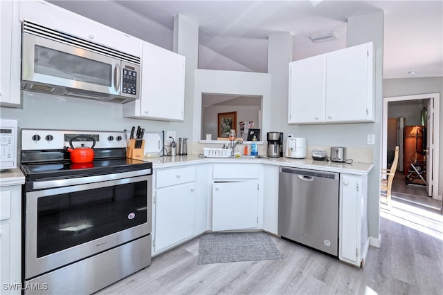 kitchen featuring white cabinets, appliances with stainless steel finishes, light countertops, and light wood-style floors