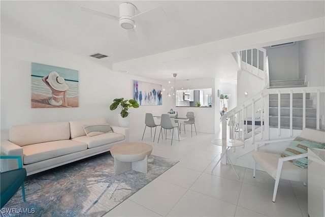 tiled living area with visible vents, stairs, and ceiling fan with notable chandelier