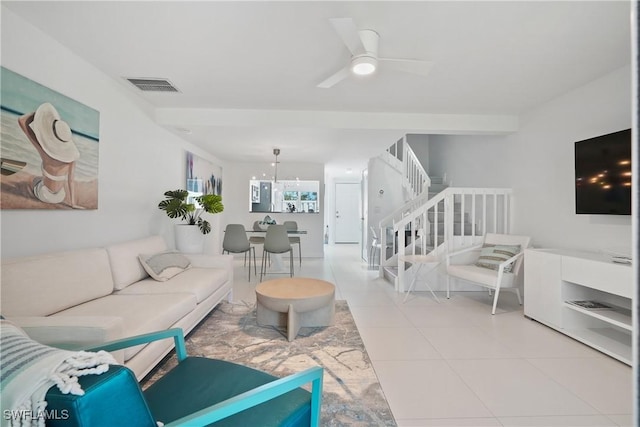 living area with light tile patterned floors, stairway, visible vents, and ceiling fan with notable chandelier