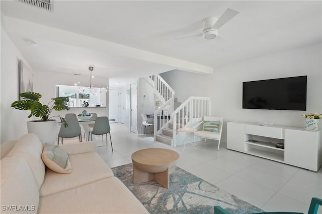 living area featuring stairway, visible vents, tile patterned flooring, ceiling fan with notable chandelier, and baseboard heating