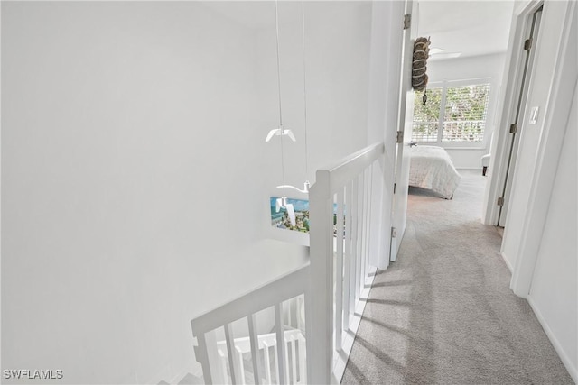 corridor with carpet flooring, an upstairs landing, and baseboards