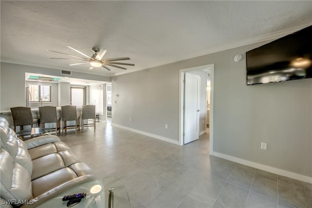 living area with tile patterned floors, visible vents, ornamental molding, a ceiling fan, and baseboards