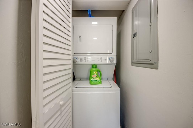 laundry room featuring electric panel, stacked washer and dryer, and laundry area