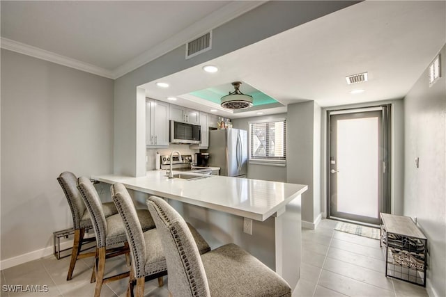 kitchen with visible vents, a breakfast bar, stainless steel appliances, a peninsula, and baseboards