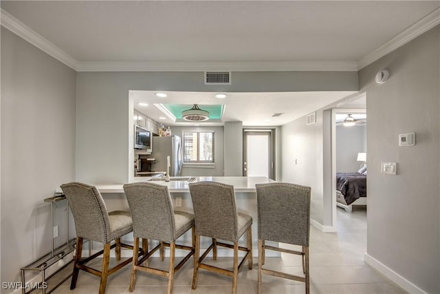 dining space featuring visible vents, baseboards, a raised ceiling, and ornamental molding