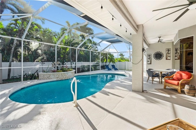 view of pool featuring glass enclosure, a fenced in pool, a fenced backyard, ceiling fan, and a patio area