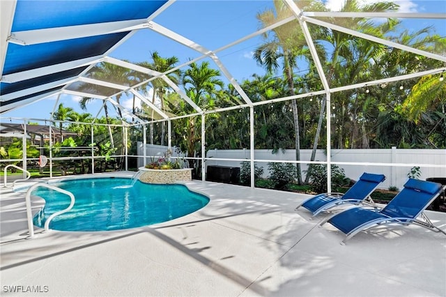 view of pool featuring glass enclosure, a patio area, a fenced backyard, and a fenced in pool