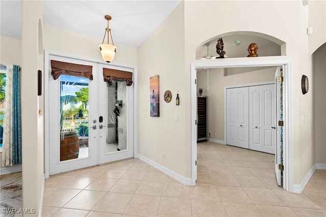 foyer entrance with light tile patterned floors, french doors, and baseboards