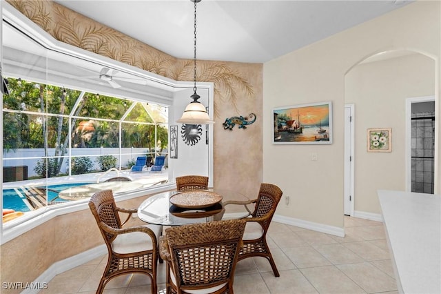 dining space with light tile patterned floors, baseboards, arched walkways, and a sunroom