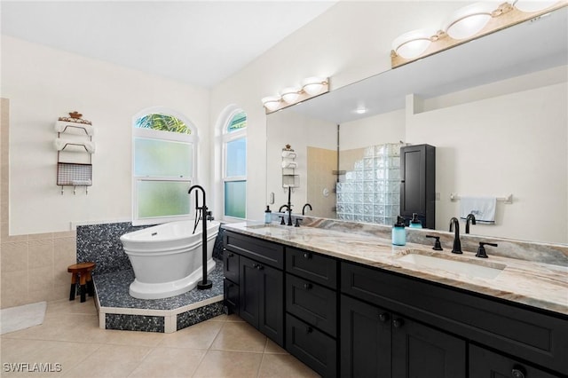 bathroom featuring tile patterned flooring, a soaking tub, double vanity, and a sink