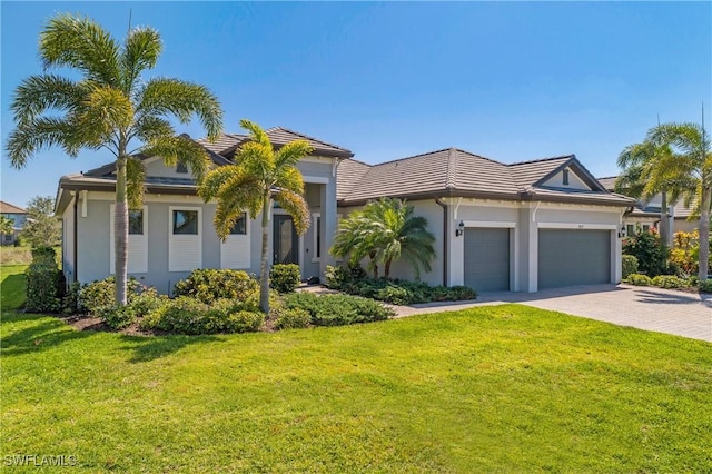 view of front of property featuring decorative driveway, a front lawn, an attached garage, and stucco siding