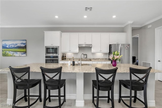 kitchen with visible vents, stainless steel appliances, a sink, a large island, and white cabinets