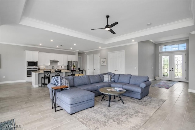 living room featuring baseboards, a tray ceiling, ornamental molding, recessed lighting, and french doors