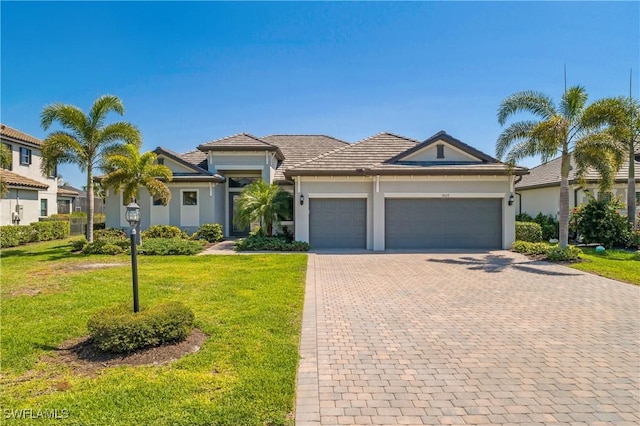 view of front facade with decorative driveway, an attached garage, a front lawn, and stucco siding