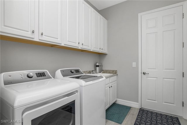 washroom featuring cabinet space, washing machine and dryer, and baseboards