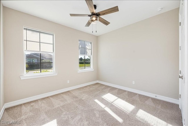 spare room featuring light colored carpet, baseboards, and ceiling fan