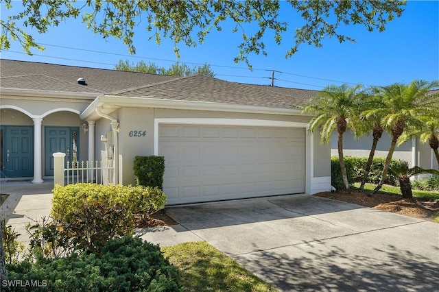 view of front of property with stucco siding, driveway, an attached garage, and roof with shingles