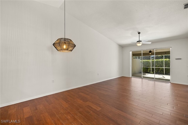 spare room with a ceiling fan, vaulted ceiling, wood finished floors, and visible vents