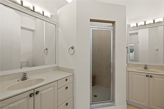 full bathroom featuring a sink, toilet, two vanities, and a shower stall