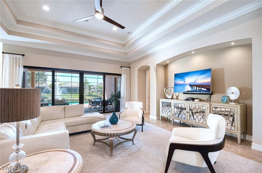 living room featuring arched walkways, recessed lighting, a raised ceiling, and ornamental molding