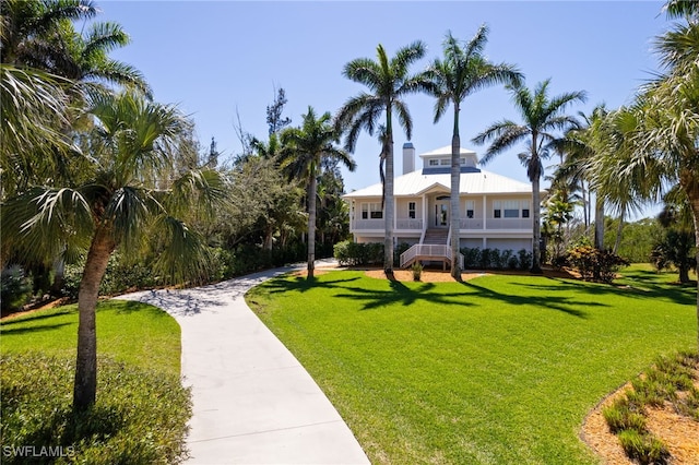 raised beach house with stairway, metal roof, and a front yard