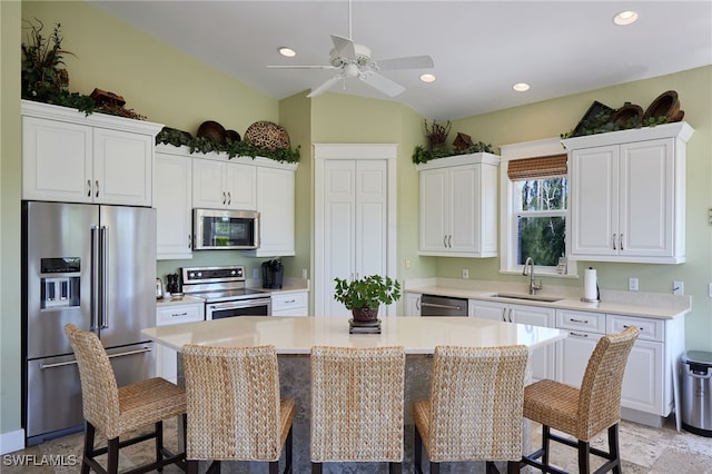 kitchen with a sink, a kitchen breakfast bar, a kitchen island, appliances with stainless steel finishes, and light countertops