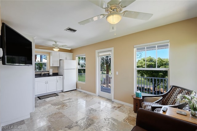 kitchen featuring visible vents, a sink, dark countertops, white cabinetry, and freestanding refrigerator