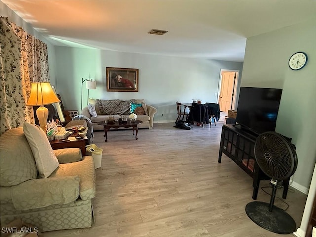 living room with visible vents, baseboards, and light wood finished floors