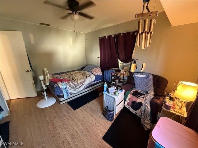 bedroom with ceiling fan, visible vents, and wood finished floors