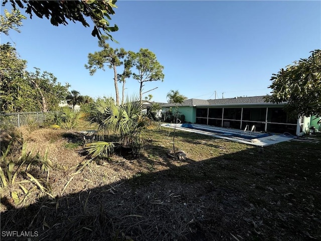 view of yard featuring fence and a sunroom