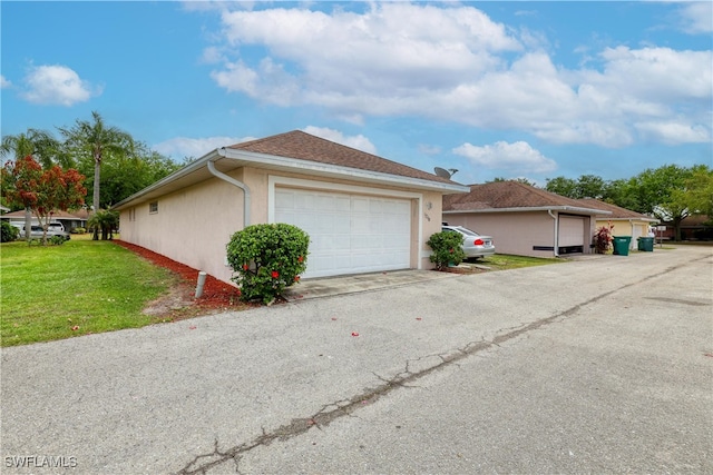 view of side of property featuring stucco siding, a lawn, and a garage