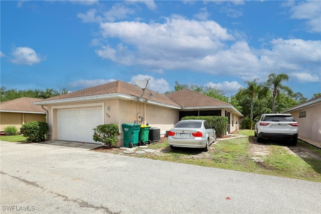 view of front facade with central air condition unit, stucco siding, driveway, and a shingled roof