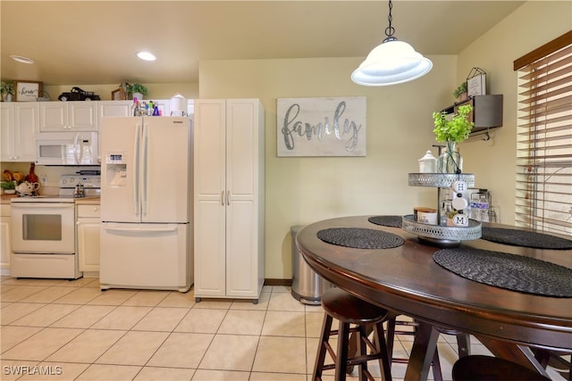 kitchen with light tile patterned floors, white appliances, white cabinets, and hanging light fixtures