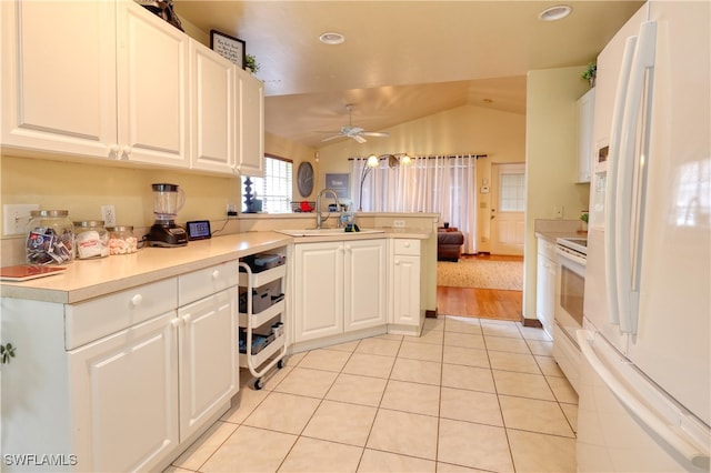 kitchen featuring white appliances, light tile patterned floors, a peninsula, a sink, and white cabinetry