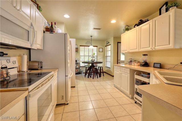 kitchen with white appliances, white cabinets, light countertops, and a sink