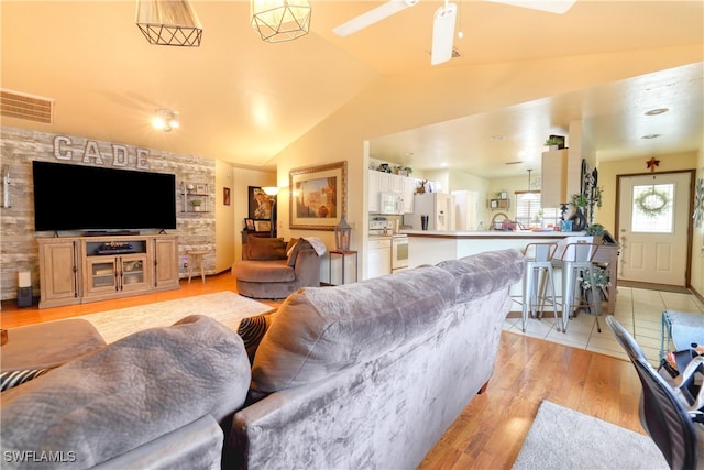 living area with visible vents, light wood-style flooring, ceiling fan, and vaulted ceiling