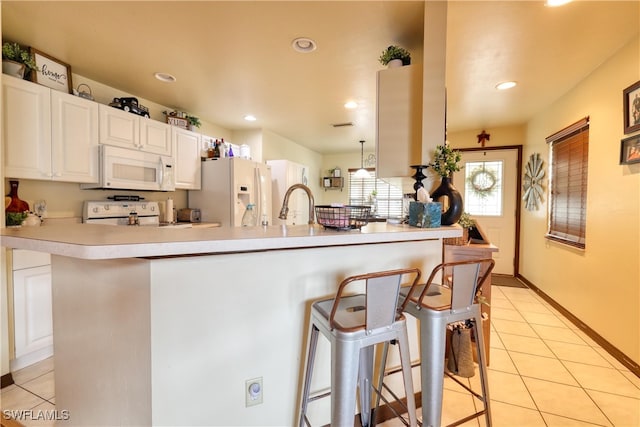 kitchen featuring white appliances, a breakfast bar area, light tile patterned flooring, light countertops, and white cabinets