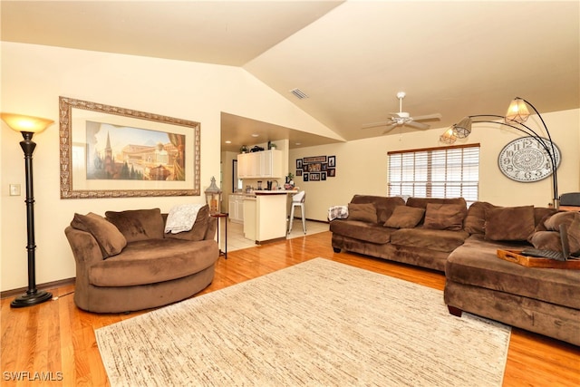 living area with light wood-type flooring, visible vents, baseboards, lofted ceiling, and ceiling fan