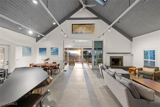 16886 Captiva Dr, Captiva, FL 33924 - living area with high vaulted ceiling, rail lighting, a fireplace with raised hearth, a ceiling fan, and beam ceiling
