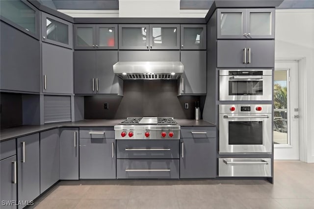 16886 Captiva Dr, Captiva, FL 33924 - kitchen featuring wall chimney exhaust hood, dark countertops, appliances with stainless steel finishes, a warming drawer, and gray cabinets
